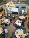 An overhead view of people sitting around six round tables and working during the Early Career Workshop.