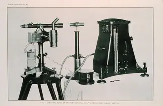 A black and white photo shows metal equipment connected wires sitting on a table.