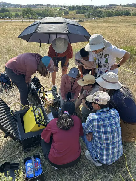 Field grouped around an electrical resistivity meter in a grassy field.