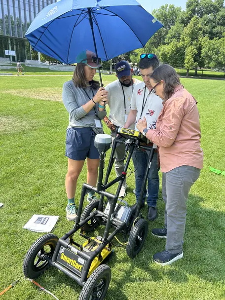 Four people conducting a ground penetrating radar survey on a university campus quad.