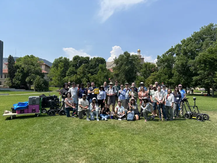 Large group of people on a campus quad with geophysics equipment near them in carts.