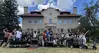Group of ~32 people in  front of one of the older Colorado School of MINES buildings along with some geophysics instruments on carts.