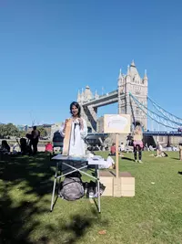 Rehemat at the 2018 London Children's Curriculum Festival. I am holding a fake sediment core and a 3D foraminifera next to Tower Bridge, London (UK).