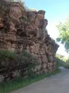 Alternating sandstone and shale layers next to a bike path.