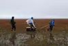 Three researchers pulling instruments across a permafrost measurement site near Barrow AK.