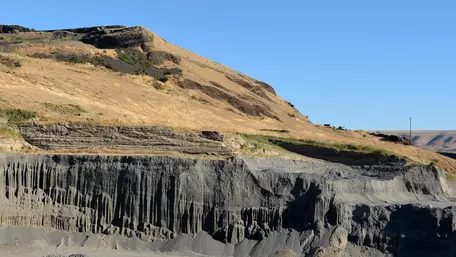 Layer of grey flood deposits near a hillside