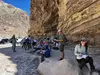 Geology field trip participants in the shade of a layered cliff