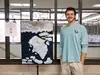Penn State Brandywine student DJ Woodward standing next to his quilt depicting a polar bear on a sheet of ice.