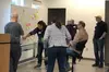 People standing near a white board and pointing at sticky notes of different colors.
