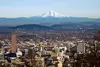 A tall, snow-capped, conical mountain is visible above a city skyline