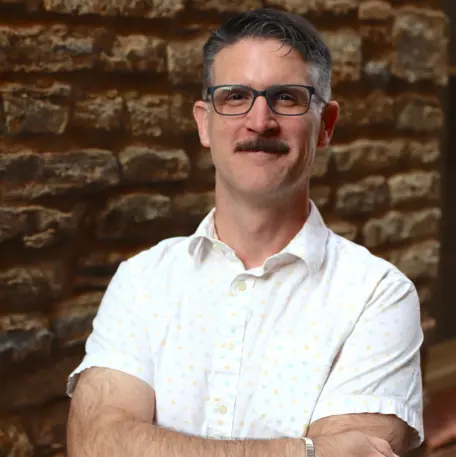 John McDaris standing in front of a stone wall.