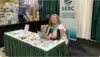 Amy sits at SERC exhibitor table at AGU