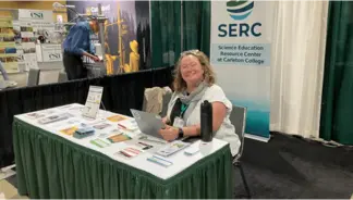Amy sits at SERC exhibitor table at AGU